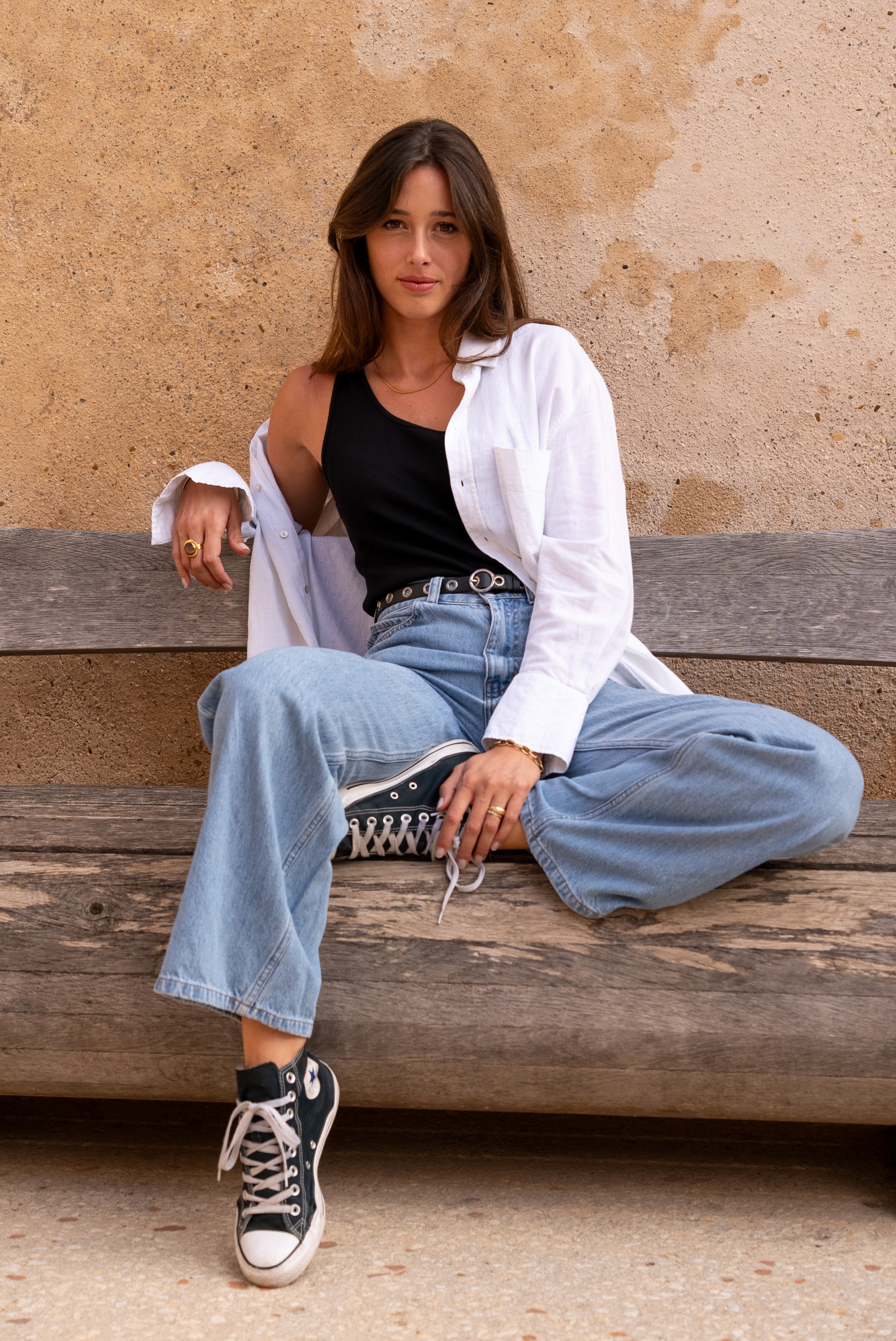 Portrait d’un mannequin femme assise sur un banc en extérieur à Marseille, lumière naturelle.