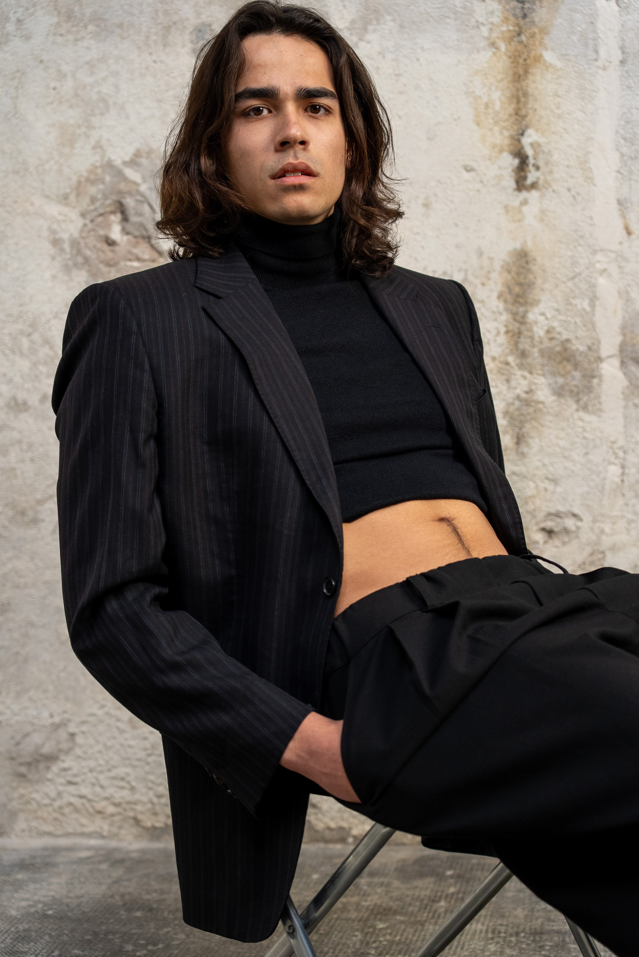 Portrait mode d’un mannequin homme en studio à Marseille, assis en costume noir, regard face caméra, ambiance éditoriale.